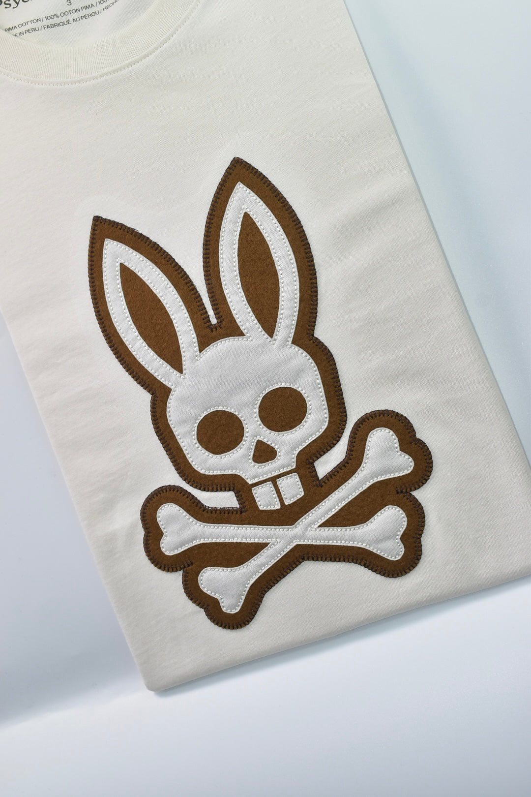 CAMISETA PSYCHO BUNNY COLECCION ORIGINAL BLANCO GRABADO CAFE Y BLANCO